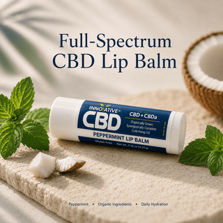 Premium full-spectrum CBD peppermint lip balm with mint leaves and coconut on a matte stone surface in soft natural lighting.