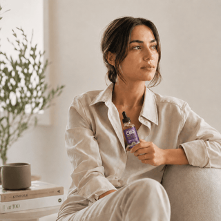 Woman holding Innovative CBD Basics full spectrum CBD tincture in a calm modern wellness lifestyle setting with soft natural light.
