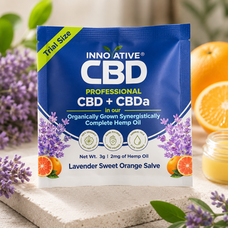 nnovative CBD Professional CBD + CBDa Lavender Sweet Orange Salve trial size packet with lavender flowers, citrus accents, and botanical wellness styling on a stone surface.