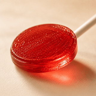 Extreme close-up of a glossy full spectrum CBD and CBDa lollipop with translucent candy texture and warm luxury lighting