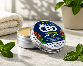 Innovative CBD Ova Muscle Rub 2oz tin open on marble counter with spa towel and mint leaves in natural light.