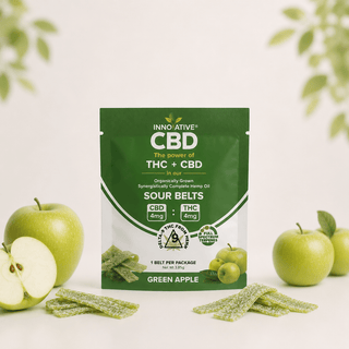 Innovative CBD Green Apple Sour Belts trial size pouch with green apple flavored THC + CBD sour belt strips on a soft cream background with fresh apples and minimalist wellness styling.