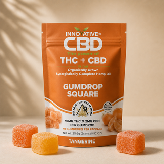 Innovative CBD Tangerine THC and CBD Gumdrop Squares pouch with sugar-coated tangerine and pineapple gumdrops on a soft neutral background.